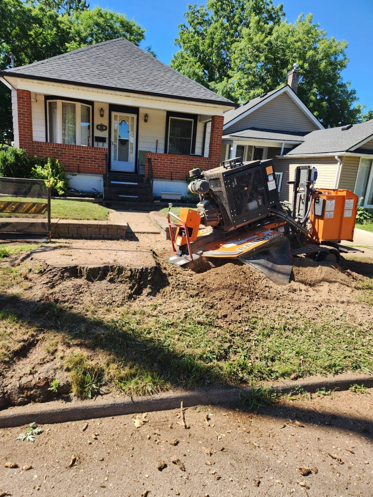 Heavy-duty stump grinder working on a large stump in front of a house